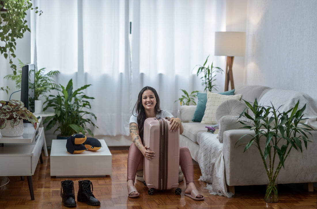 Woman sitting on the floor holding her pink suitcase