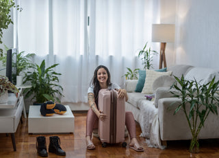 Woman sitting on the floor holding her pink suitcase