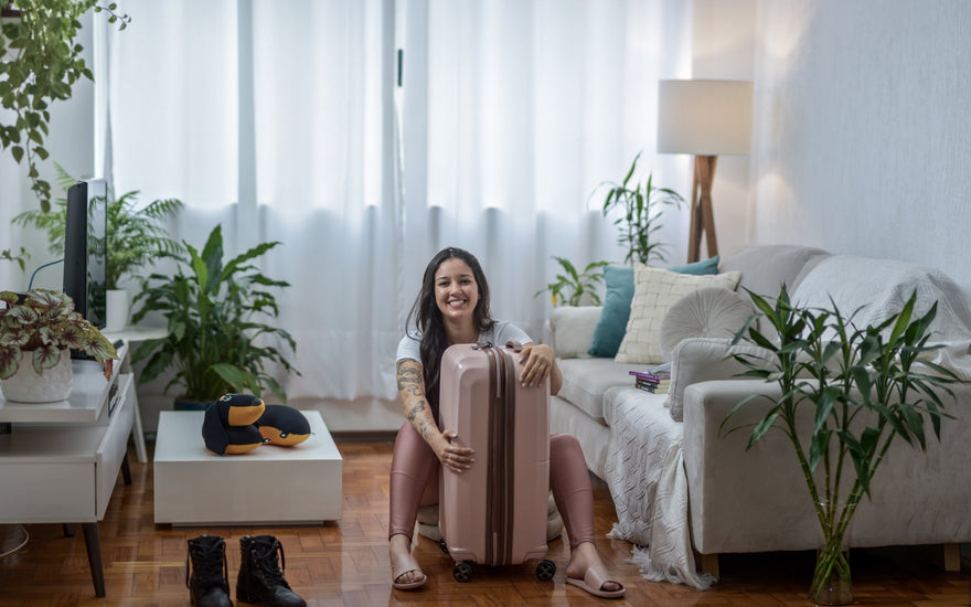Woman sitting on the floor holding her pink suitcase