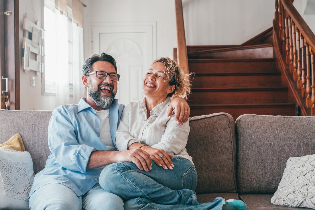 Happy couple laughing while sitting on their living room couch.