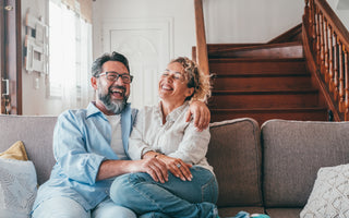 Happy couple laughing while sitting on their living room couch.