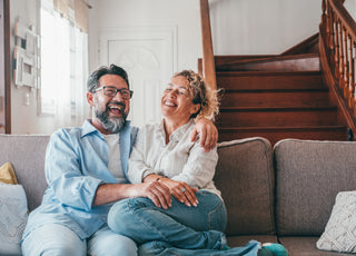 Happy couple laughing while sitting on their living room couch.