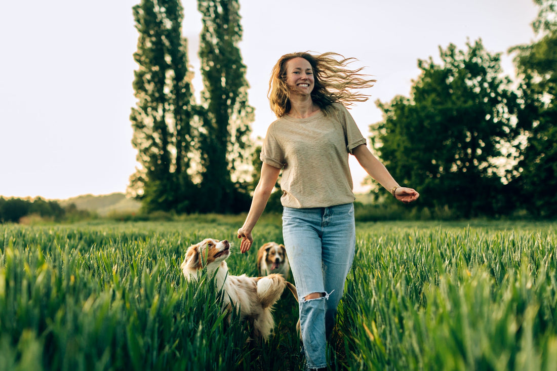 Happy woman running a field with her dogs. 