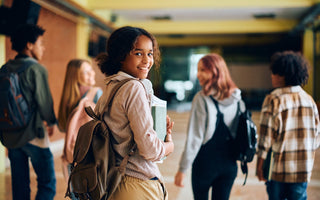 Happy teenage girl in high school hallway looking at the camera. 