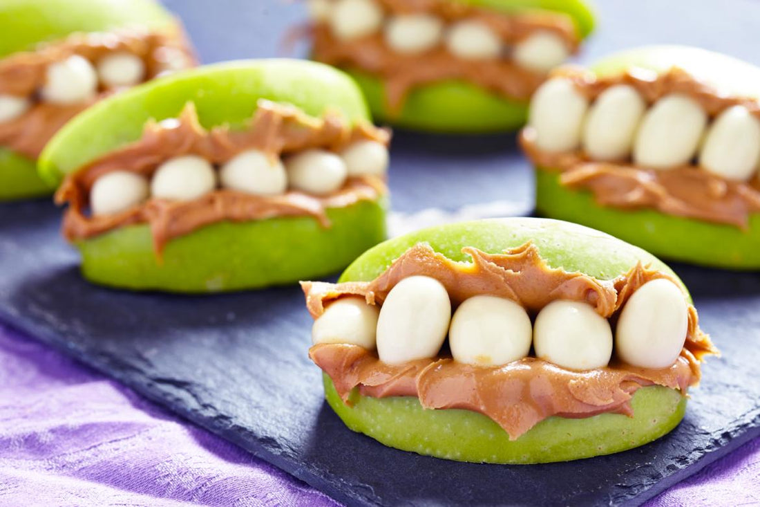 Green apple slices that have been decorated as monster mouths using peanut butter and sunflower seeds.