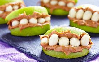 Green apple slices that have been decorated as monster mouths using peanut butter and sunflower seeds.