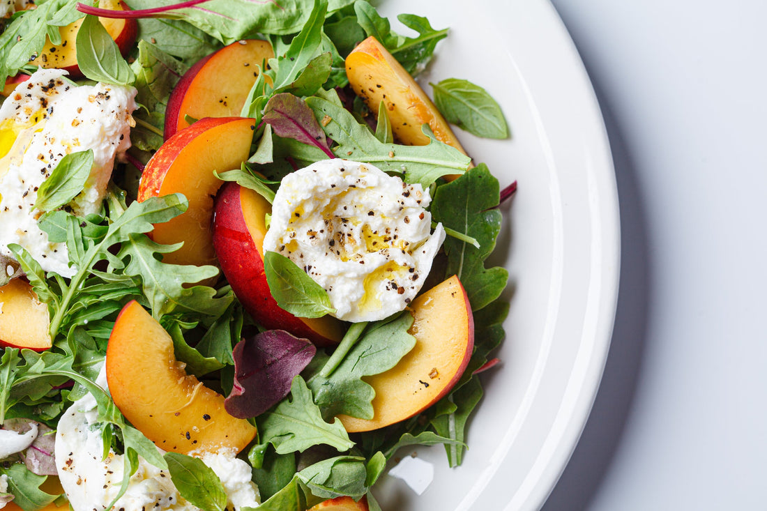 Burrata and peaches summer salad on a white background. 
