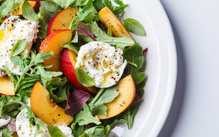 Burrata and peaches summer salad on a white background. 