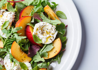 Burrata and peaches summer salad on a white background. 