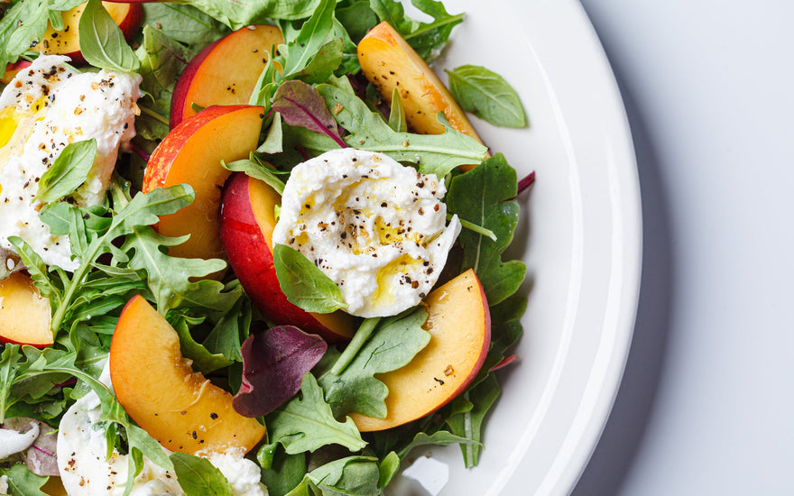 Burrata and peaches summer salad on a white background. 