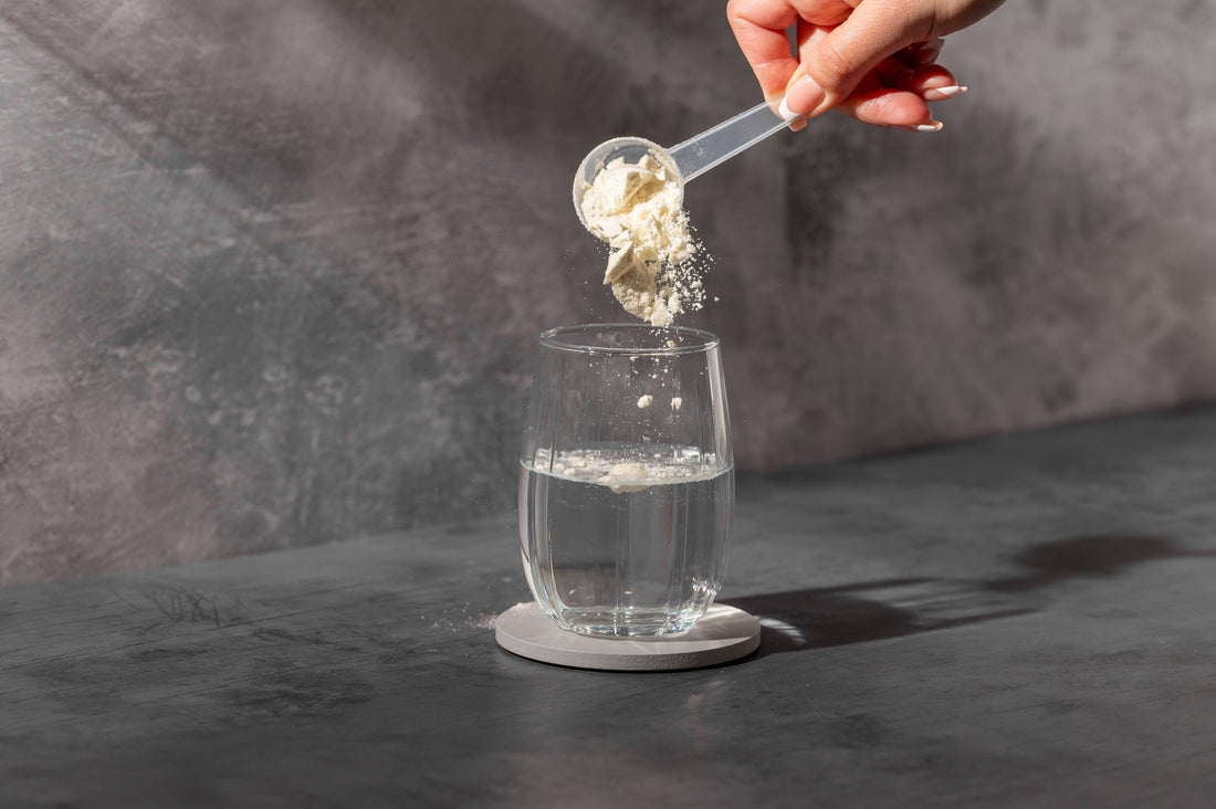 Pouring white powder supplement into a glass of water. 
