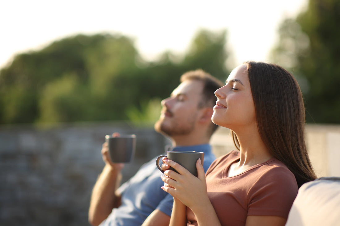 Couple drinking coffee and breathing while sitting on a terrace.