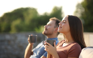 Couple drinking coffee and breathing while sitting on a terrace.