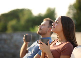 Couple drinking coffee and breathing while sitting on a terrace.