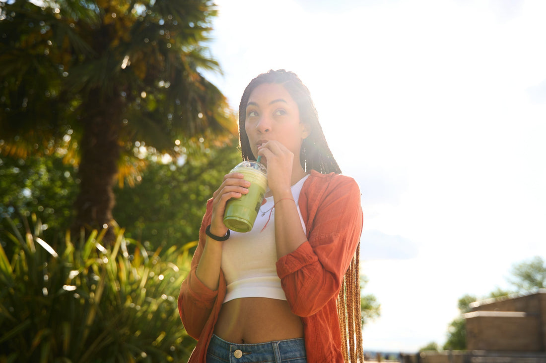 Young woman enjoying a green smoothie outdoors during the summer. 