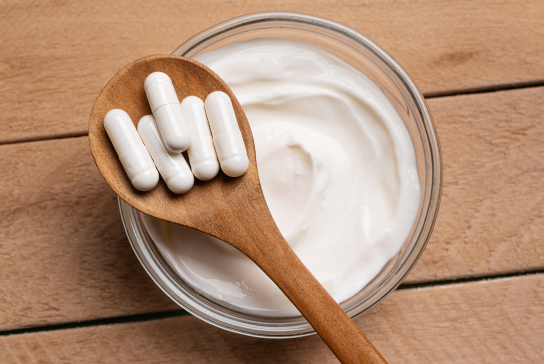 Probiotic capsules and bowl of yogurt on wooden table