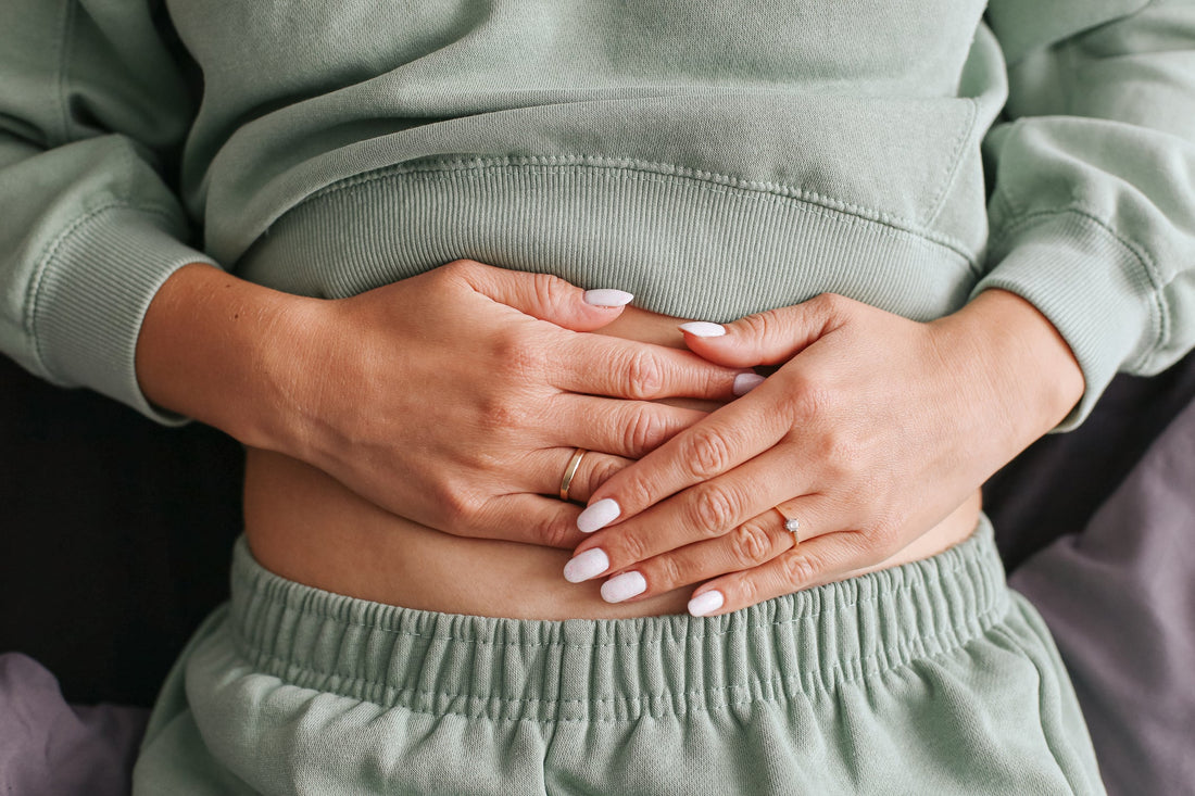 Woman laying on her back holding her stomach with her hands.