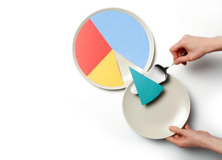 Hands using a pie server to transfer a piece of colored paper from a pie chart to a plate.