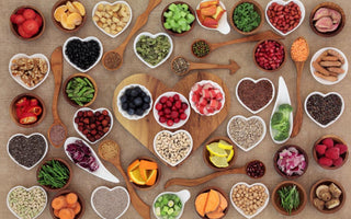 A top-down view of an array of superfoods in white dishes of various sizes spread out on a tabletop.