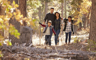 Family of four walking through the autumn woods together.