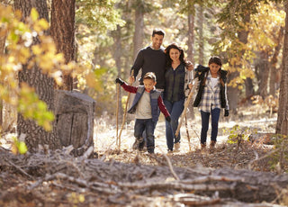 Family of four walking through the autumn woods together.