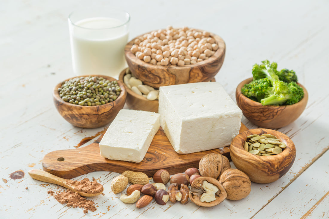 An array of plant-based foods that are known to contain protein arranged on and around a wooden cutting board.