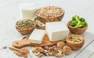 An array of plant-based foods that are known to contain protein arranged on and around a wooden cutting board.