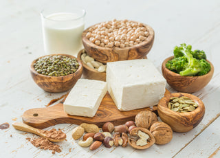 An array of plant-based foods that are known to contain protein arranged on and around a wooden cutting board.