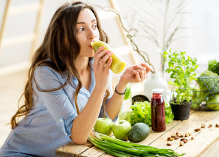 Woman leaning on her kitchen counter while drinking a healthy green drink. 