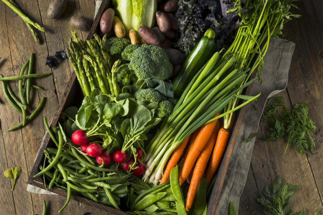 Wooden crate filled with carrots, broccoli, radishes, and other vegetables.