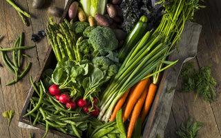 Wooden crate filled with carrots, broccoli, radishes, and other vegetables.