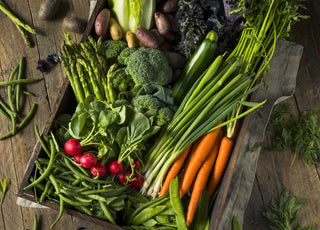 Wooden crate filled with carrots, broccoli, radishes, and other vegetables.