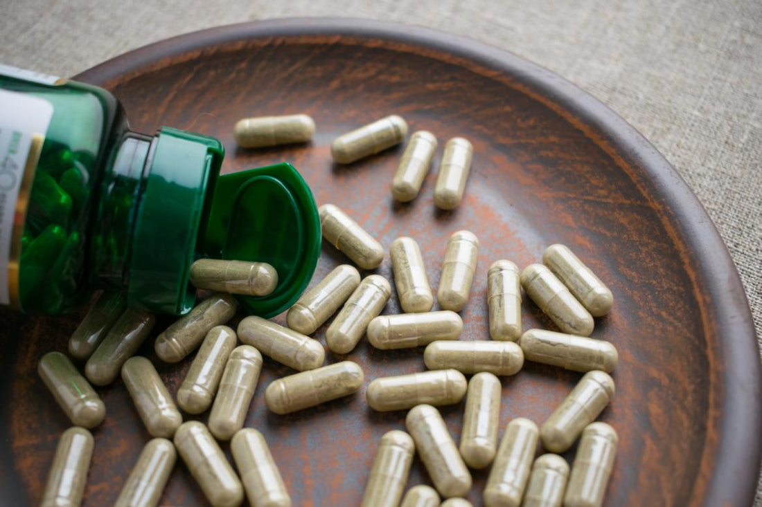 Open bottle of supplements spilling out on a wooden tray.