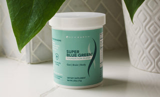 New Earth's Super Blue Green sitting on a counter net to a potted plant.