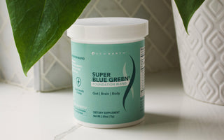 New Earth's Super Blue Green sitting on a counter net to a potted plant.