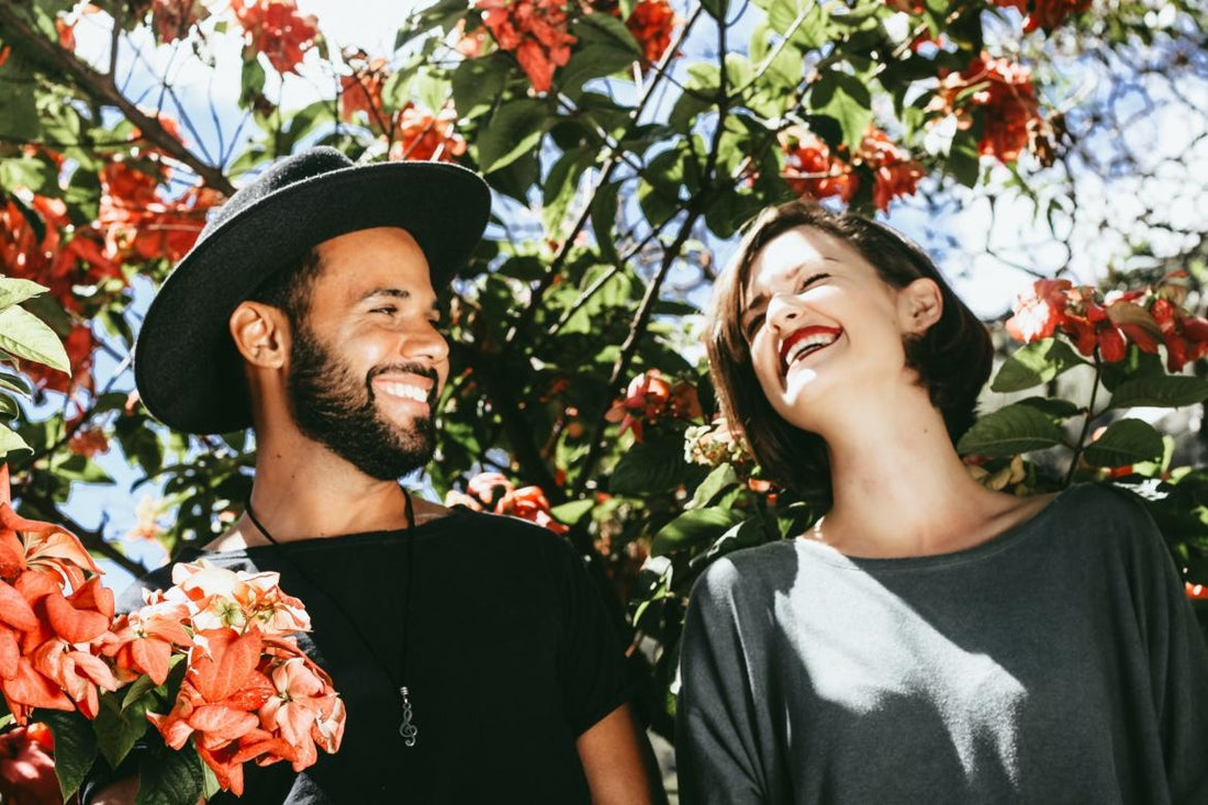 Happy couple laughing together amongst blooming flowers.