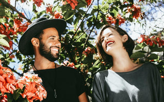 Happy couple laughing together amongst blooming flowers.