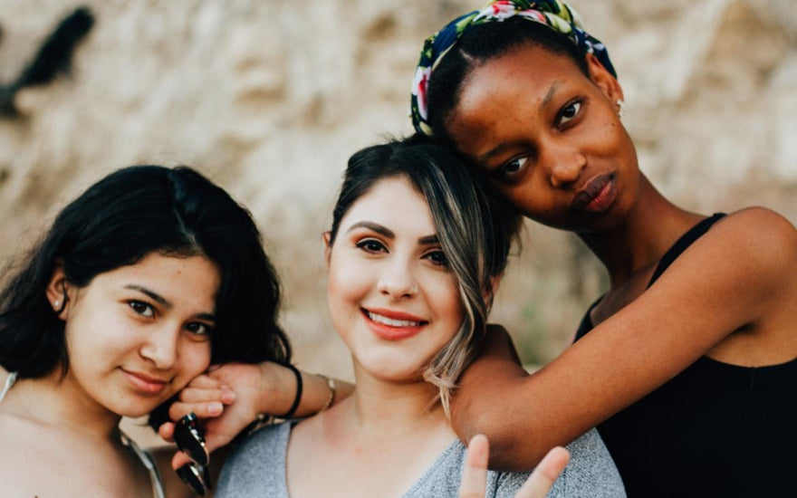 Three diverse women posing together.