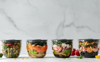 Four glass jars filled with pre-made meals sitting on a countertop.  