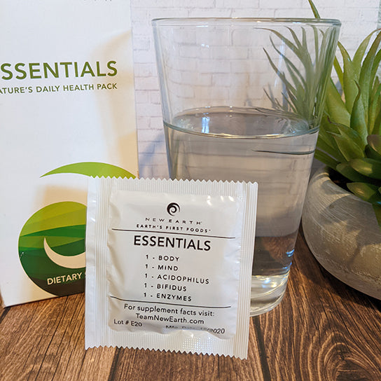 A packet of New Earth's Essentials propped up against a glass of water and a box of the same product. 